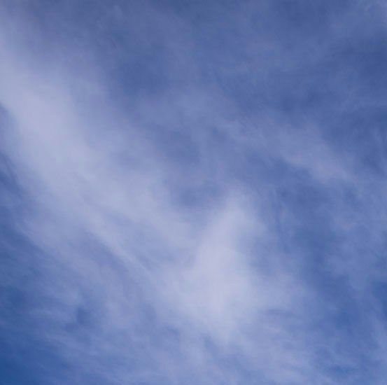 Ein Windrad auf einem Rapsfeld mit strahlend blauem Himmer mit ein paar Schleierwolken
